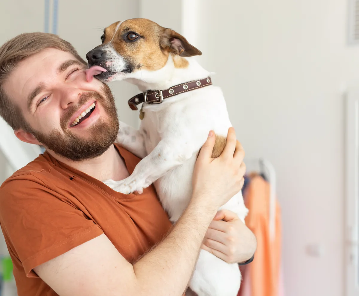 A young man being affectionate with his dog at home