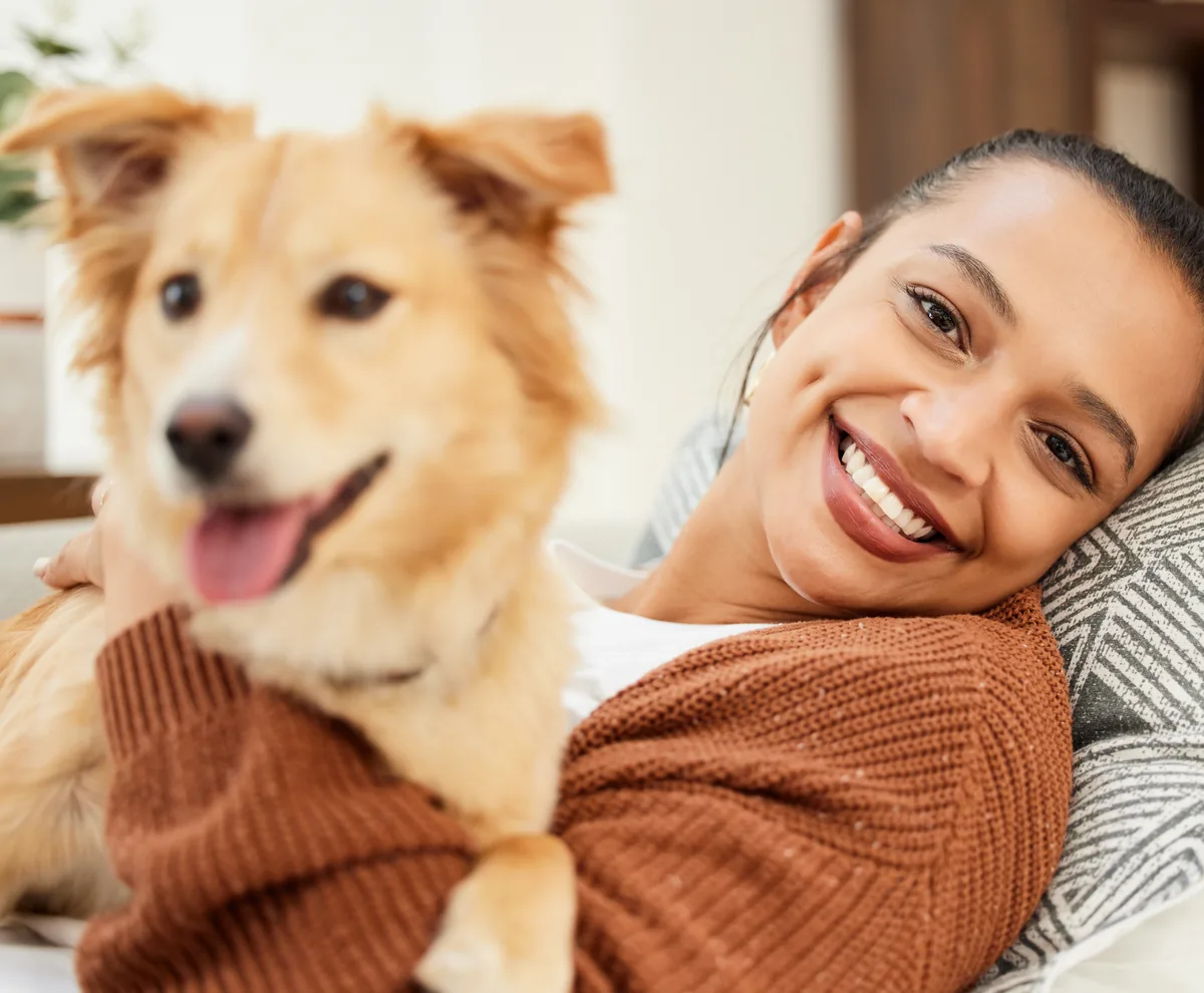 A smiling woman holding her dog at home